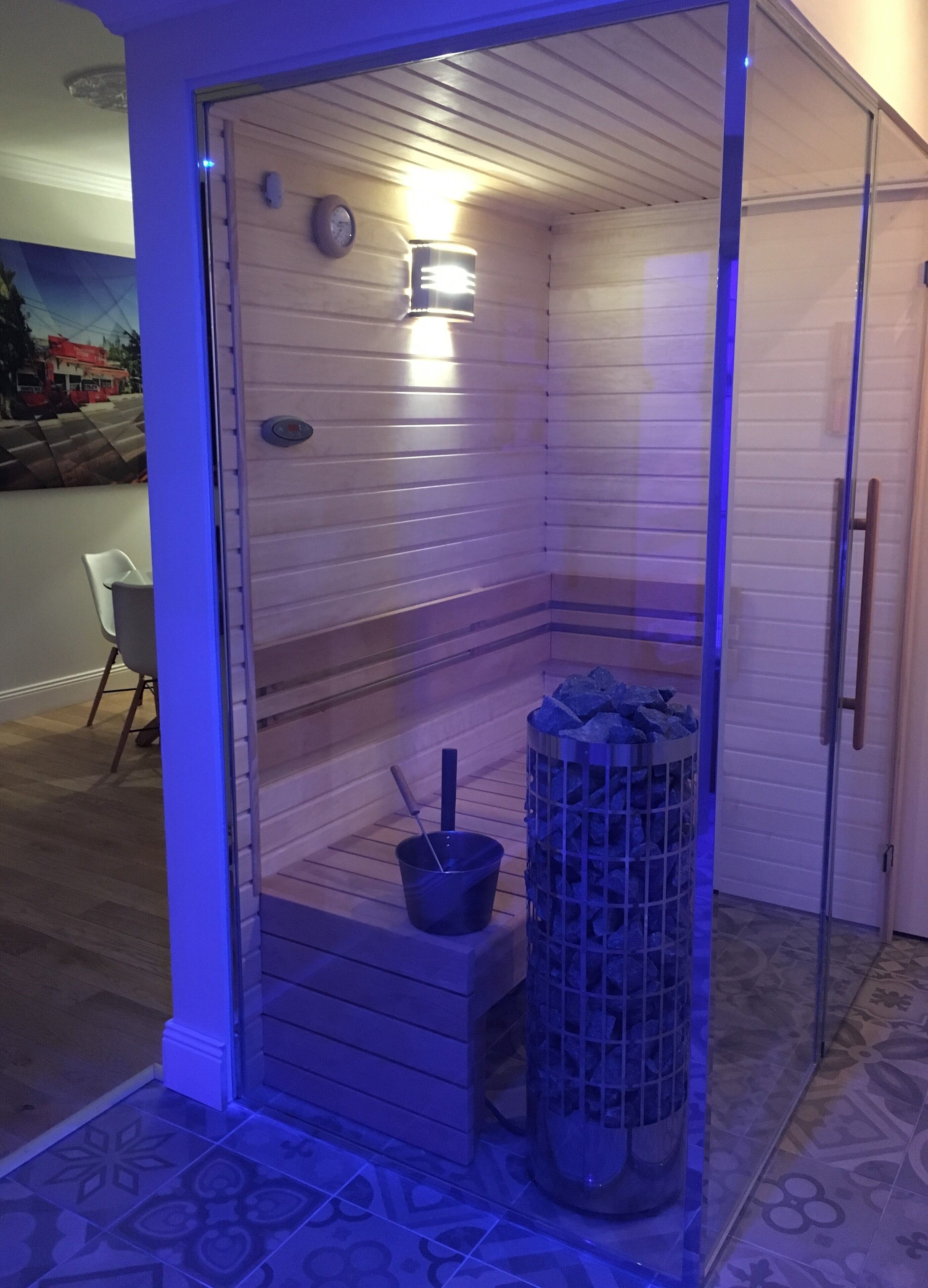 Una sauna con interior de madera, un balde y un recipiente lleno de piedras.