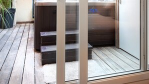 Un baño moderno con tragaluz, bañera de hidromasaje y terraza de madera.