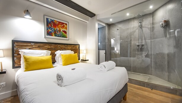 Habitación de hotel moderna con una cama grande, ducha y un cuadro en la pared.