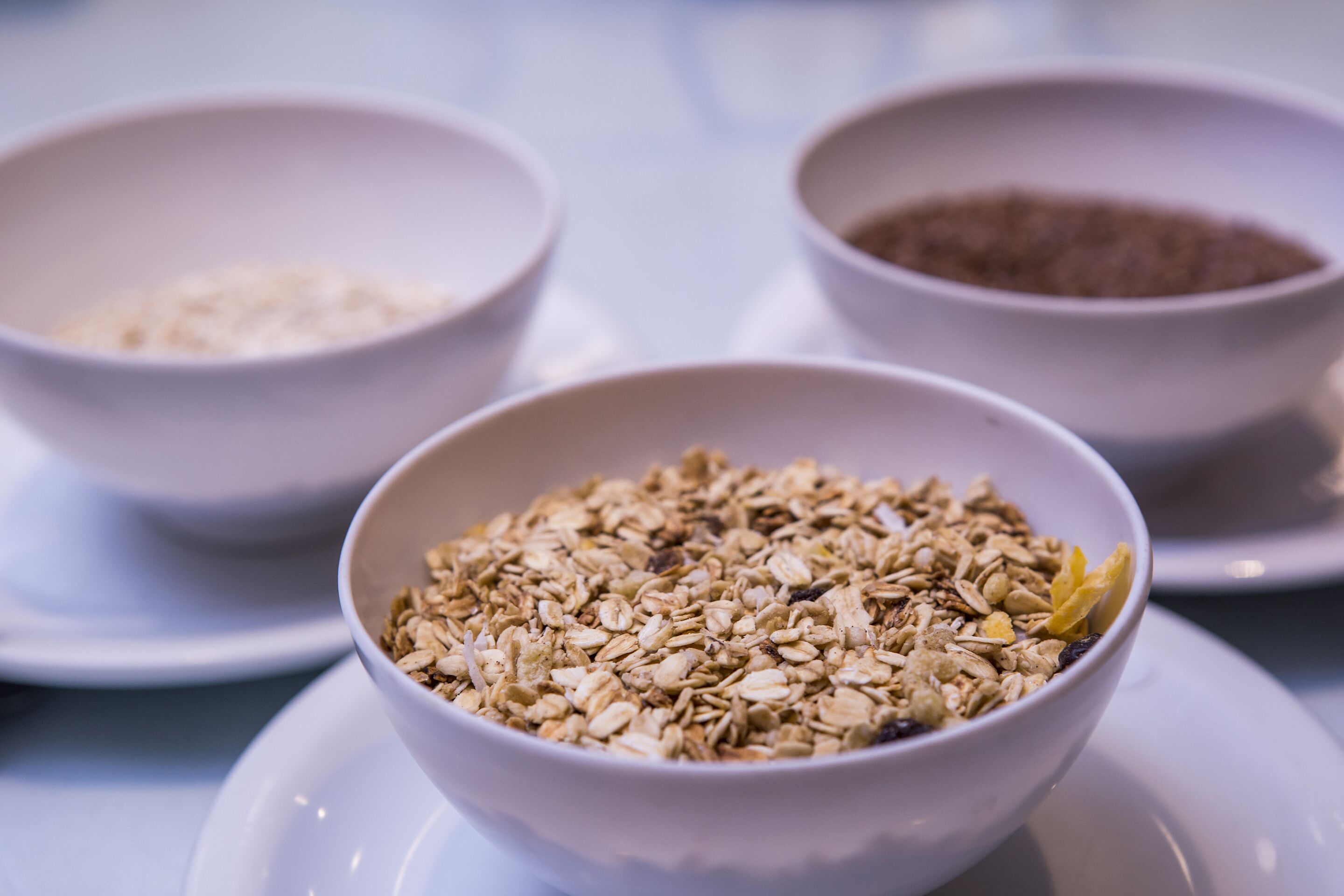 Three bowls of granola on white plates.