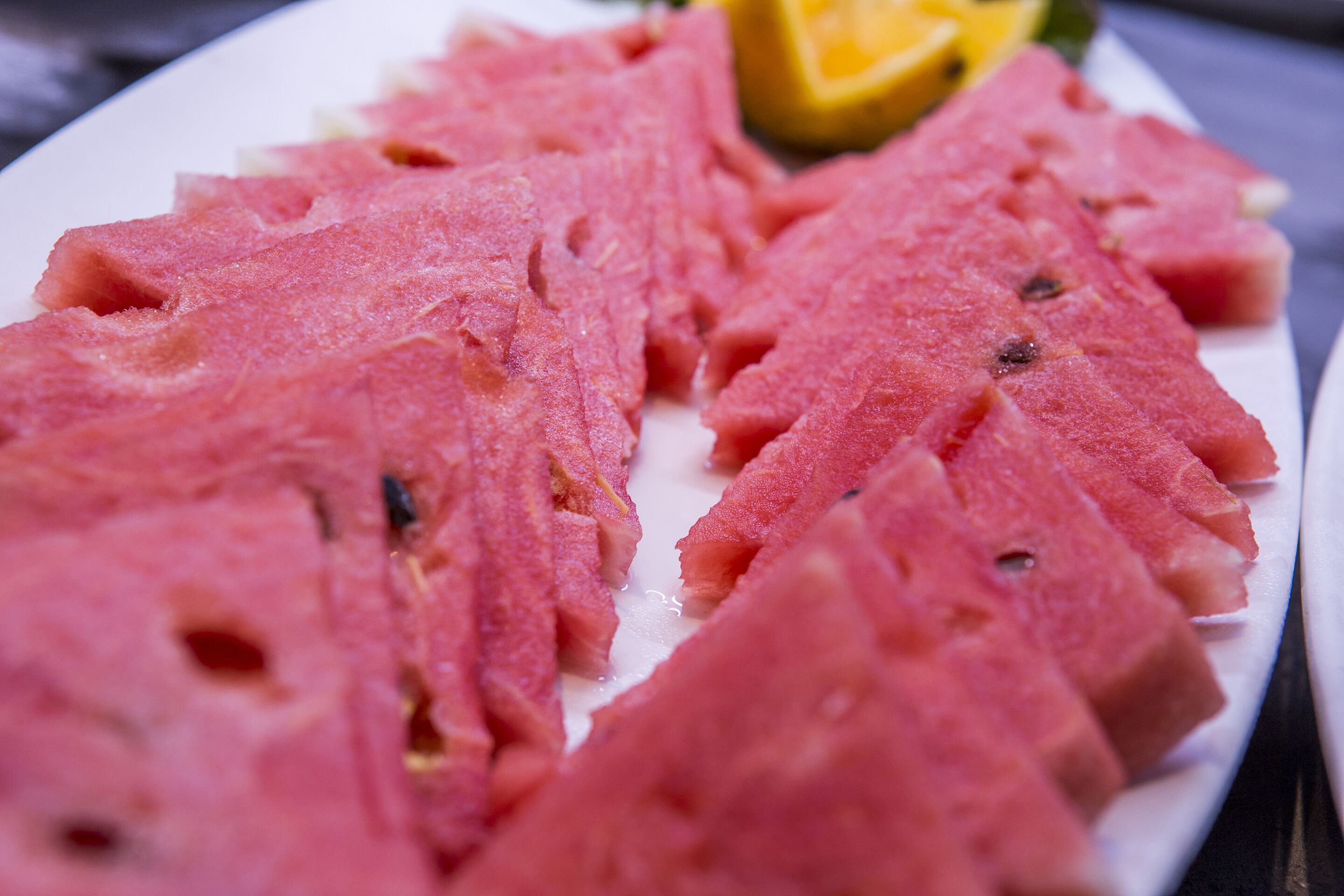 Une assiette de viande tranchée, accompagnée d’une tranche de citron.