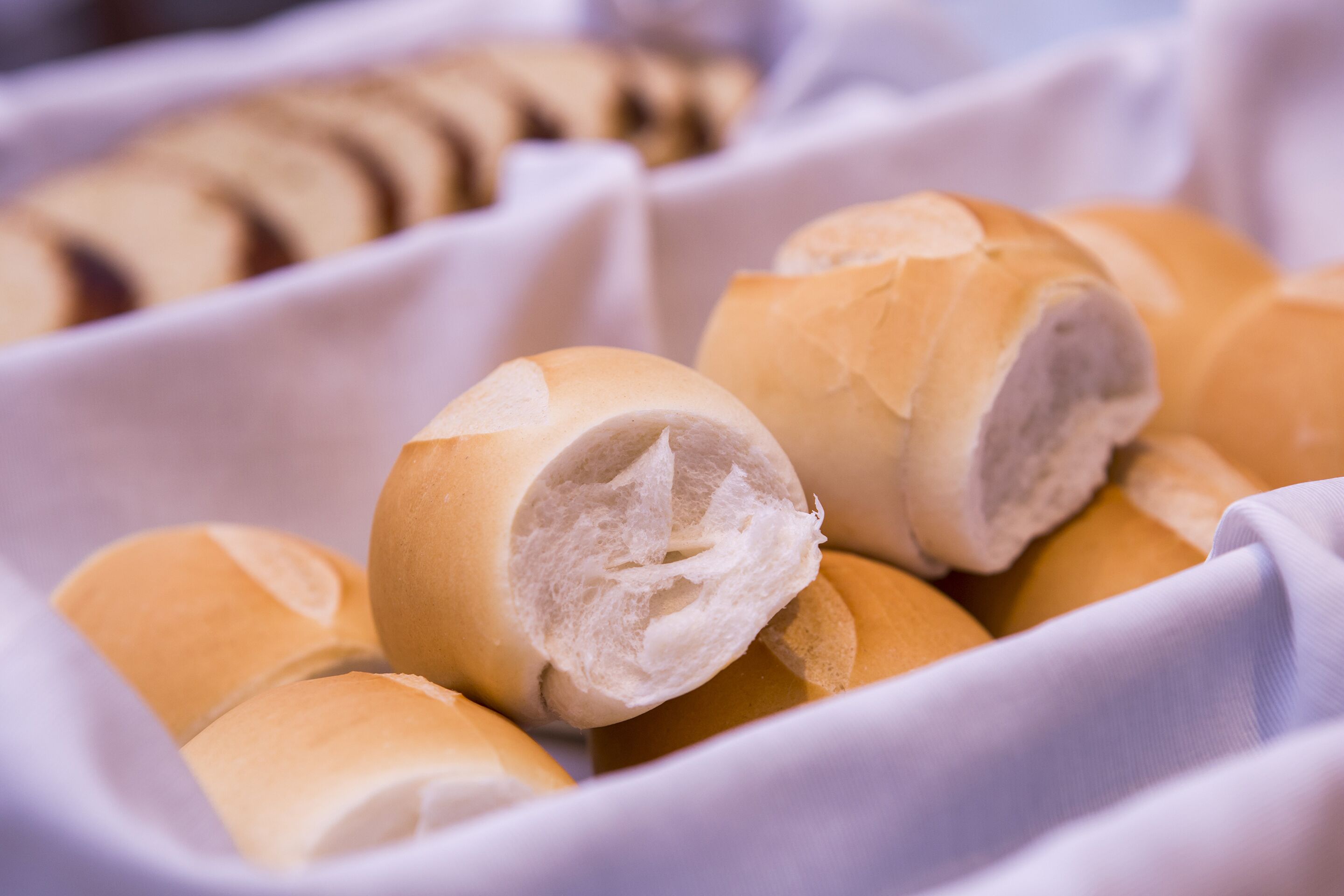 Uma cesta de pães, alguns com recheios à mostra.
