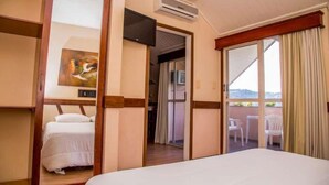 Quarto de hotel com cama, quadro, ar condicionado, televisão e varanda com vista.
