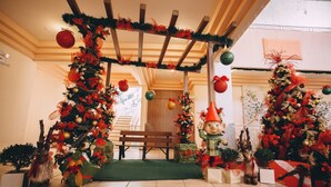 Um espaço interior decorado com pérgola de madeira, árvores de Natal e enfeites festivos.