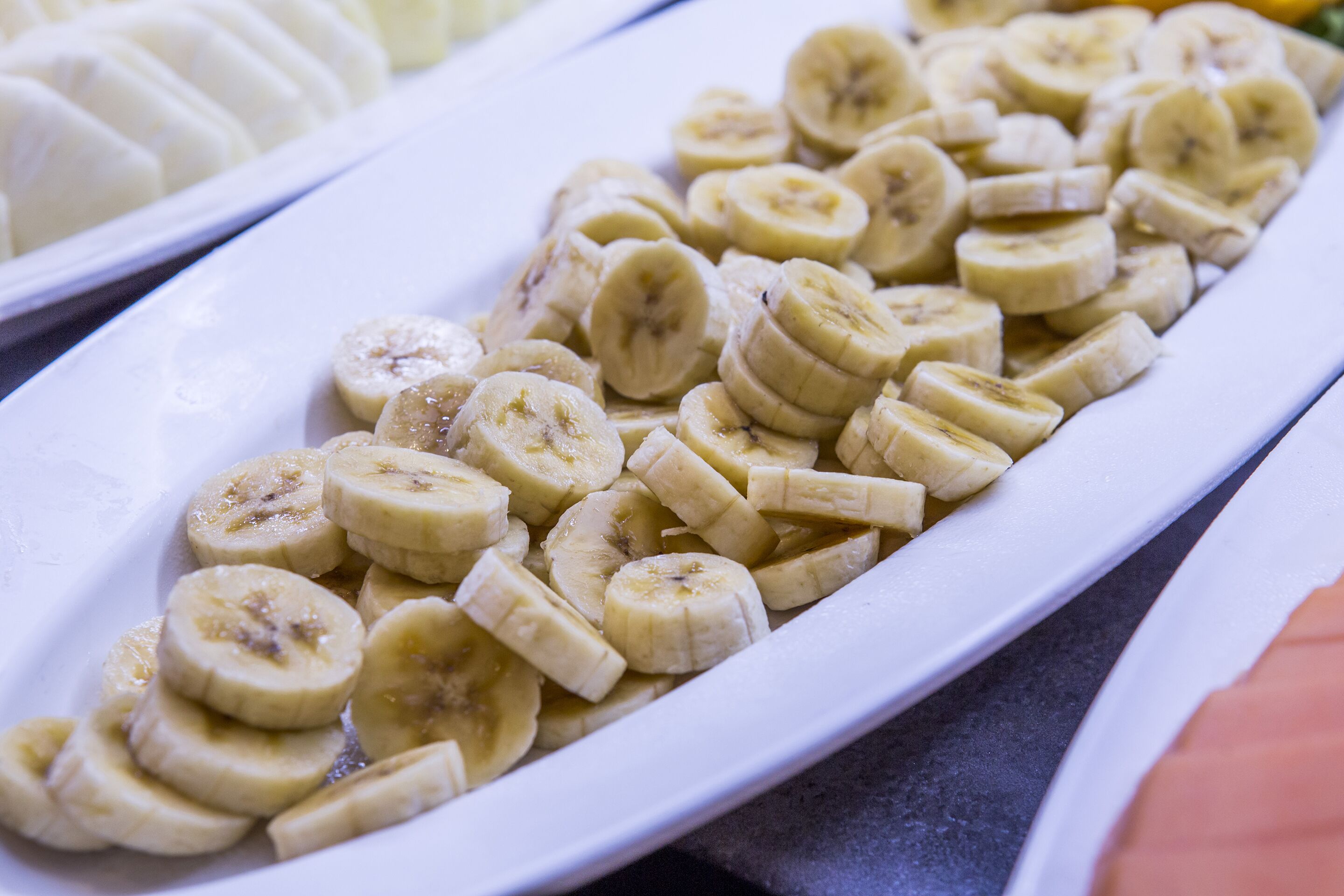 Une assiette blanche sur laquelle des tranches de bananes sont disposées en rangée.