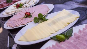 A table with various food items including sliced meats and cheeses, arranged on white plates.