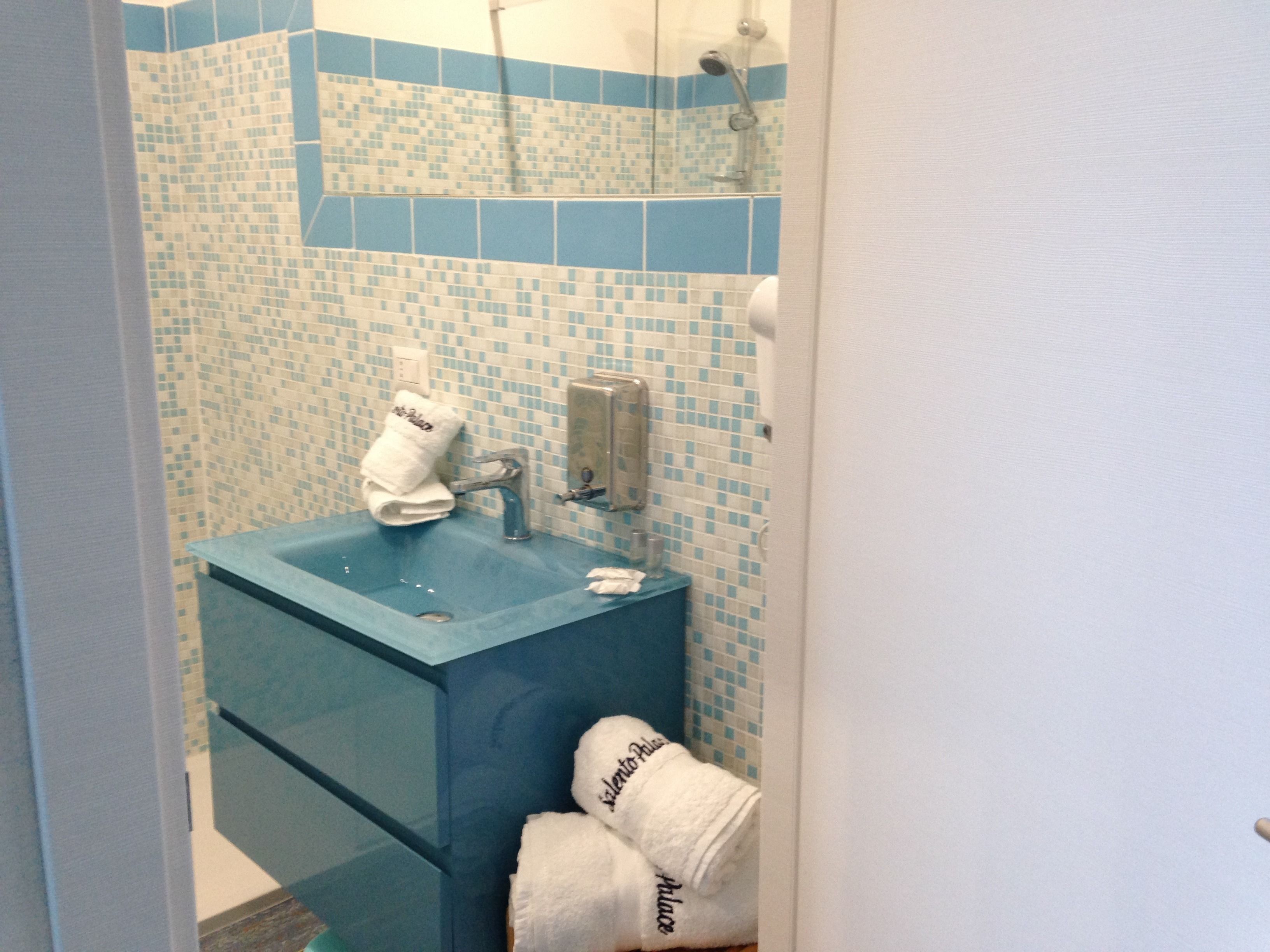 A bathroom with a blue sink, a towel rack with a folded towel, and a shower area.