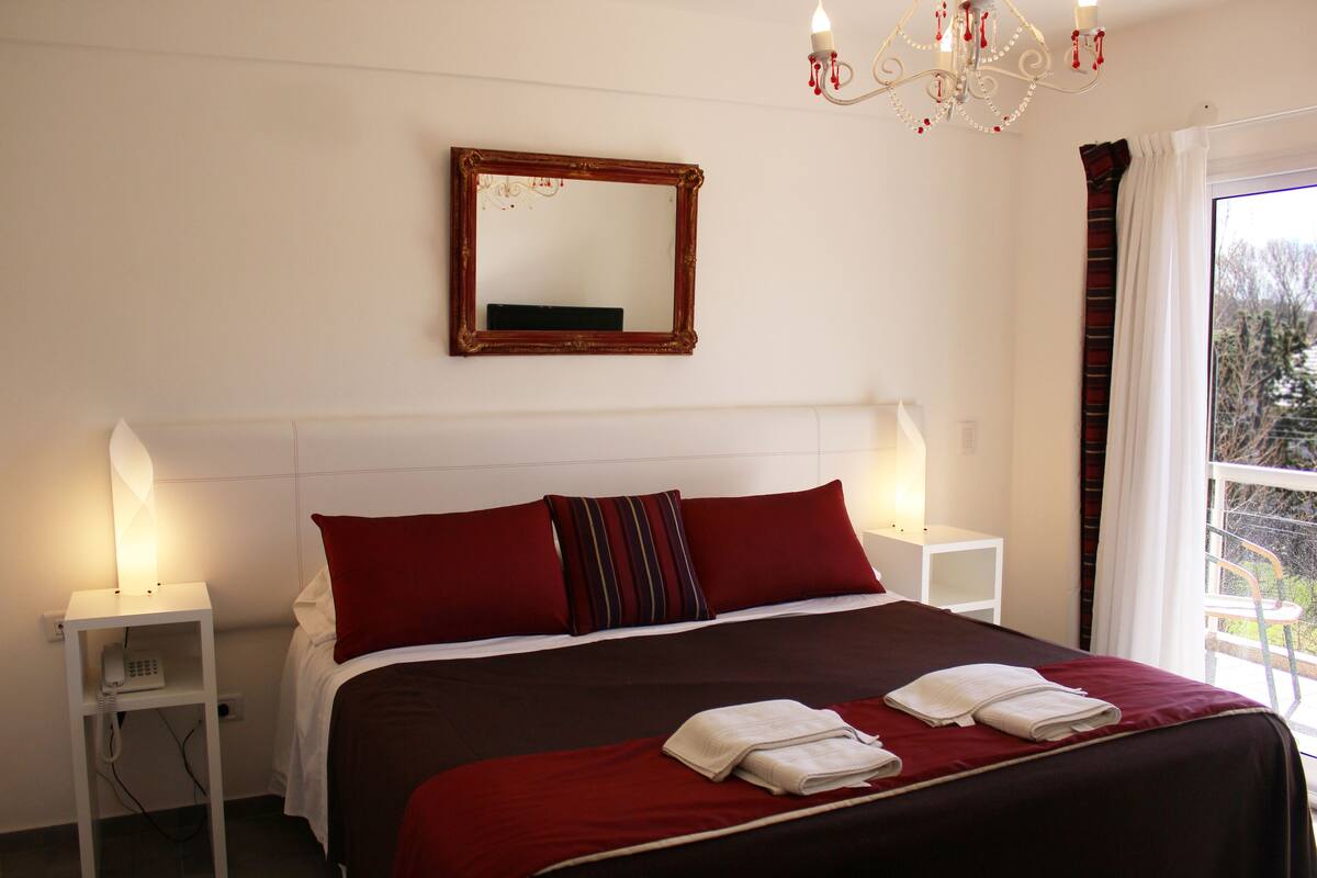 Ein Hotelzimmer mit einem großen Bett, zwei Nachttischen, einem Spiegel und einer Chandeliebre.