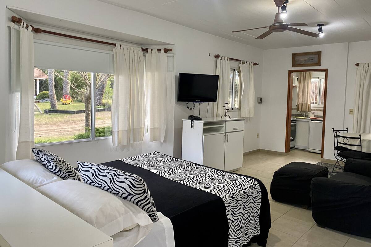 Ein Hotelzimmer mit zwei Betten, einem Fernseher, einer Küchenzeile und Blick ins Freie.