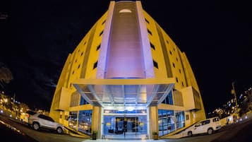 A modern hotel with a central entrance, a glass facade, and a symmetrical design.