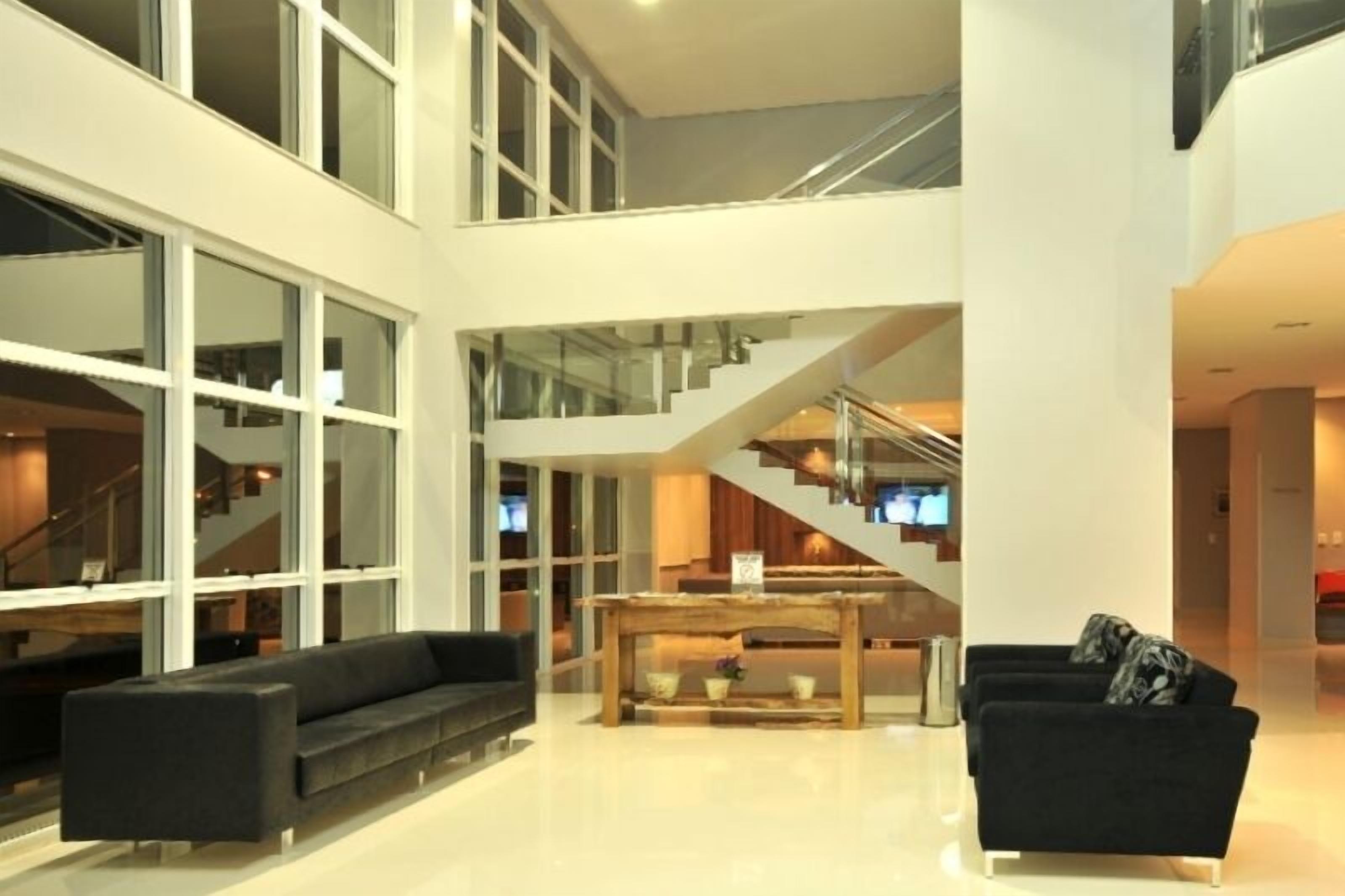Un intérieur spacieux et moderne, doté d’un plafond haut, d’un escalier reliant deux étages et d’un coin salon avec un canapé et une table basse.