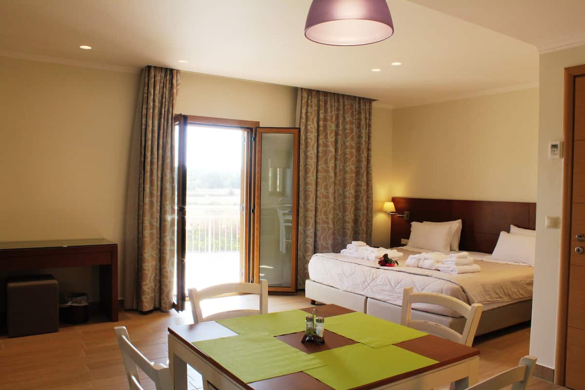 A hotel room with a bed, a desk, a chair, and a table.