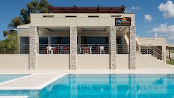 En sÀsongsöppen utomhuspool, parasoller och solstolar