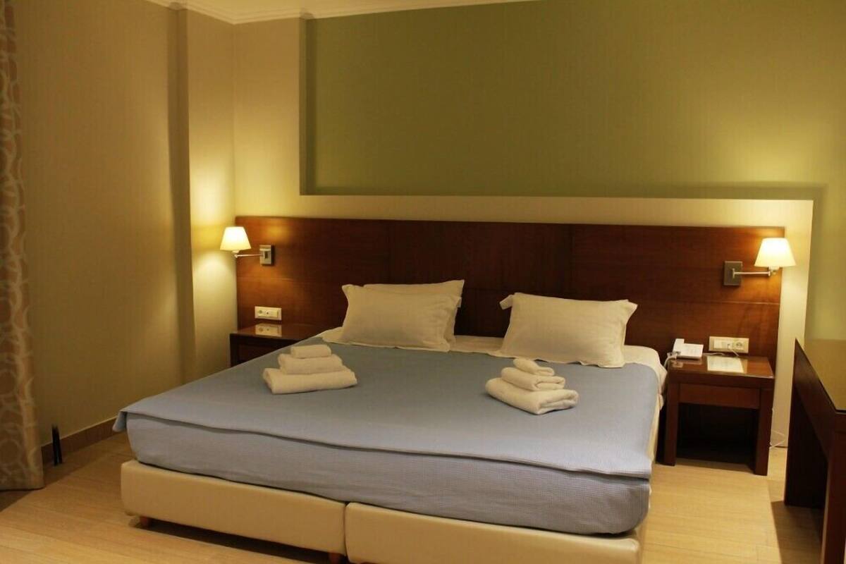 A hotel room with a large bed, two bedside tables, and a nightstand.