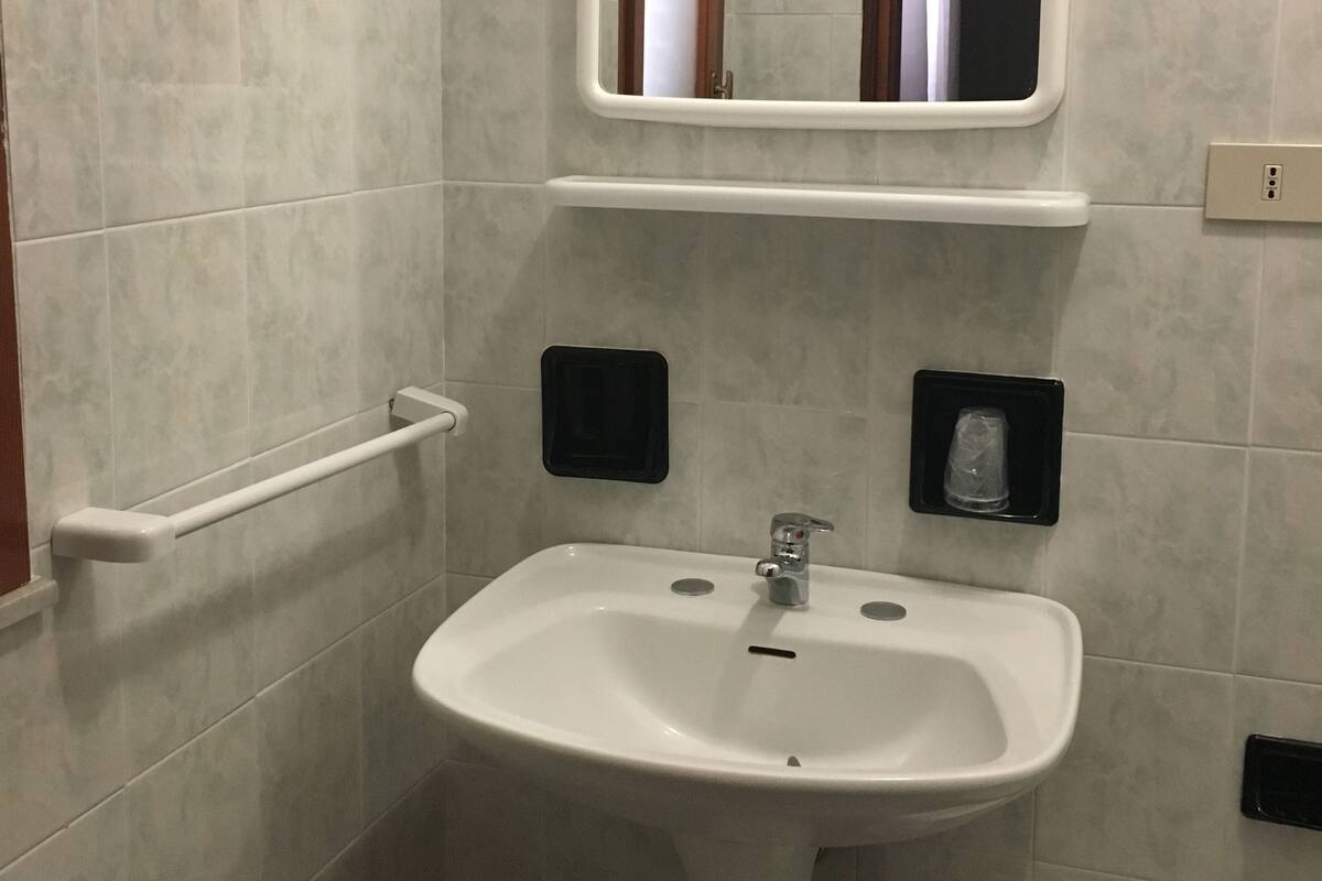 A bathroom with a white sink, a mirror, and a towel rack.