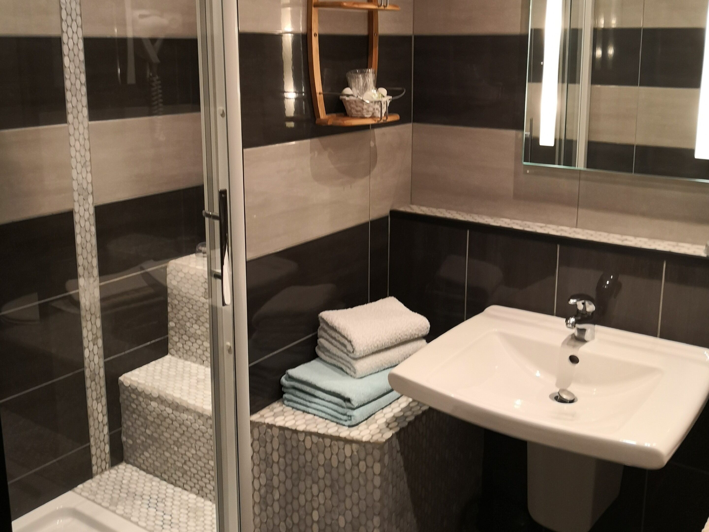 Une salle de bain avec une douche à parois de verre, un lavabo et un miroir.