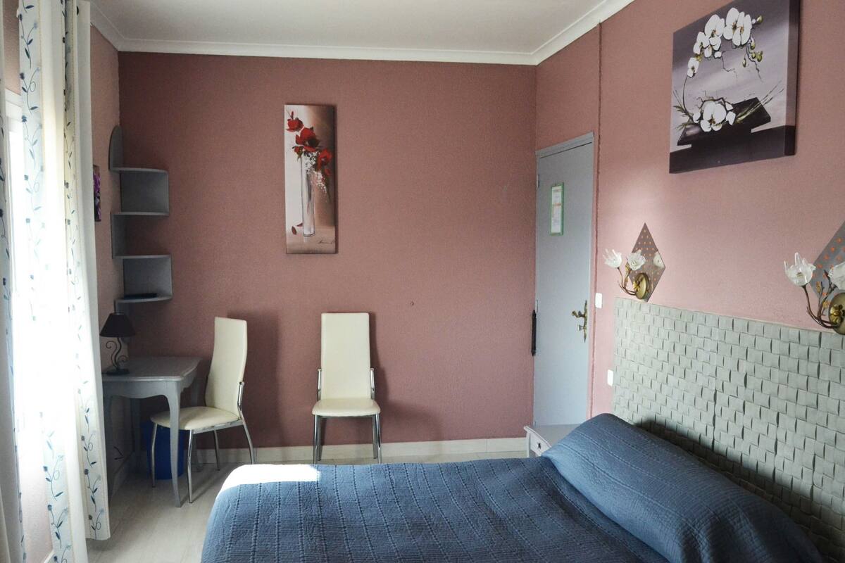 A bedroom with a bed, two chairs, a desk, and a door.
