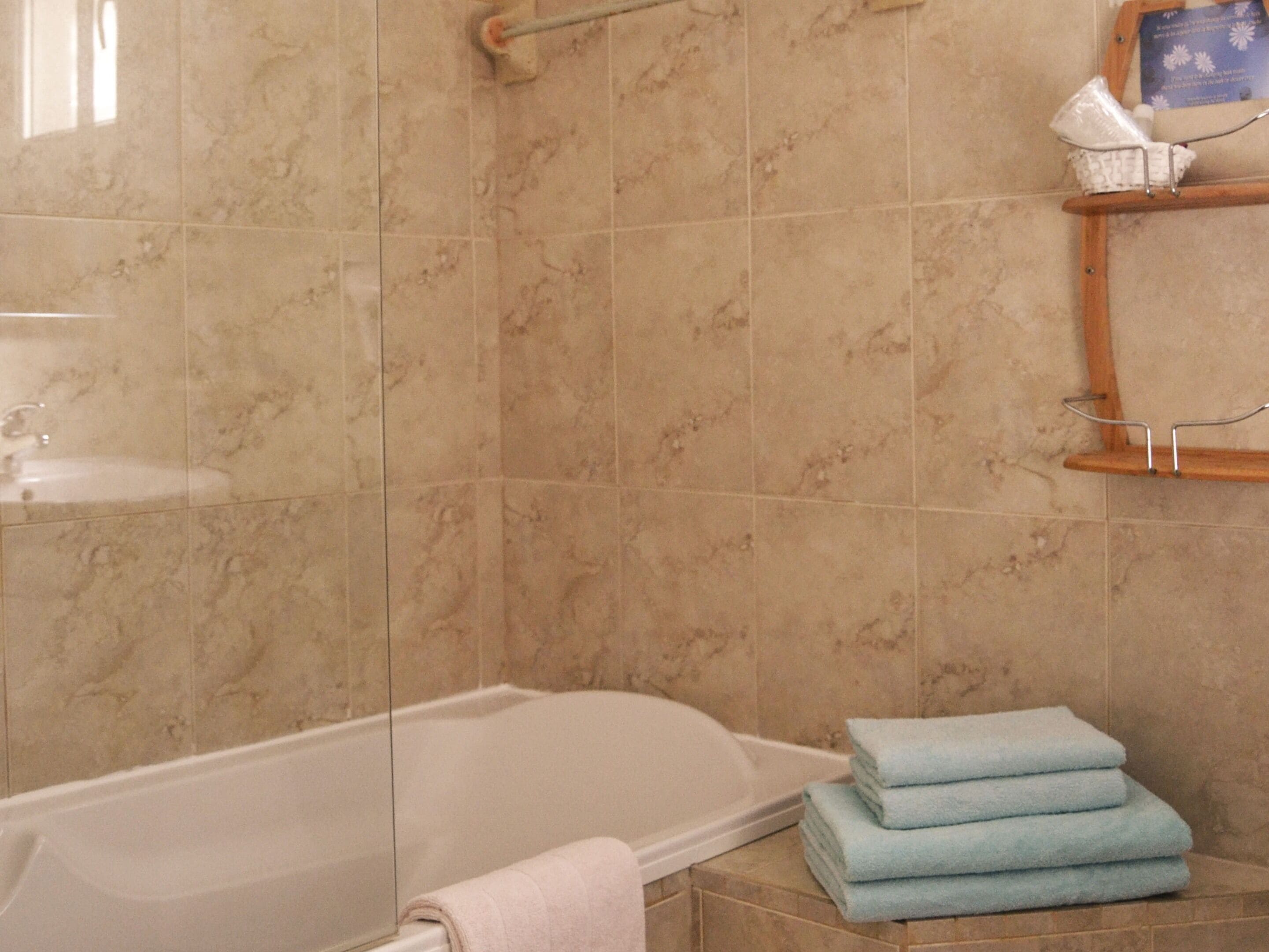 Une salle de bain avec une baignoire, un lavabo et un porte-serviettes où sont pliées des serviettes.