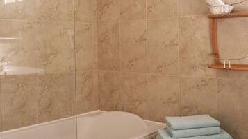 Une salle de bain avec une baignoire, un lavabo et un porte-serviettes où sont pliées des serviettes.