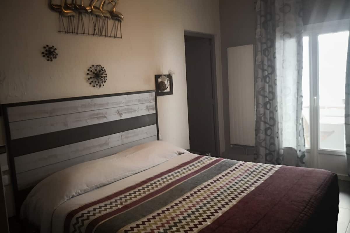 A bedroom with a wooden headboard, a patterned bedspread, and decorative wall art.