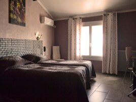 Habitación de hotel con dos camas, una silla, un escritorio, una ventana con cortinas y un teléfono instalado en la pared.