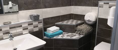 A modern bathroom with a white sink, a mirror, a towel rack, and a toilet.
