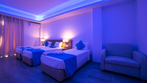 A hotel room with three beds, a sofa, and a ceiling light. - Flora Maria Hotel (Ayia Napa)