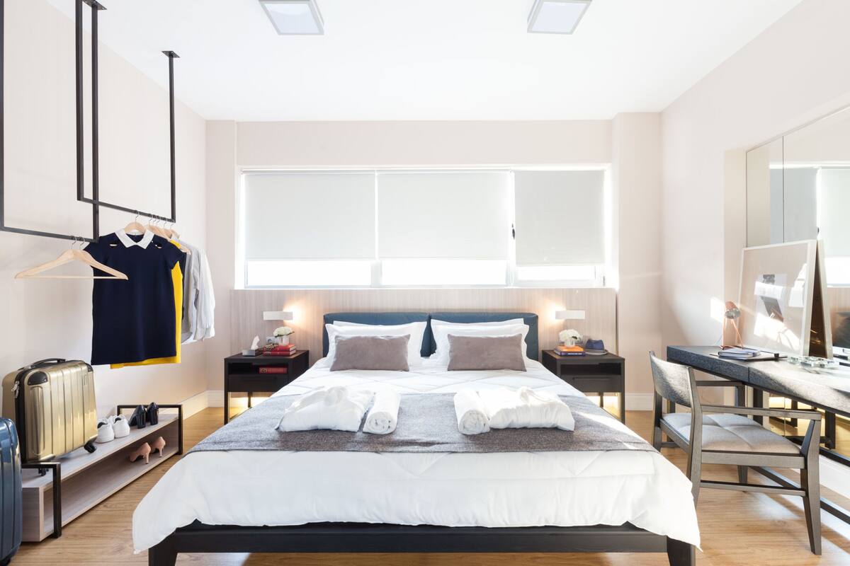 Ein modernes Hotelzimmer mit einem großen Bett, Nachttischen, einem Schreibtisch und einem Kleiderschrank.