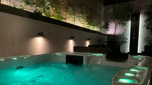 A hot tub with a waterfall feature, surrounded by tiled walls and potted plants. - 47 Luxury Suites (Athens)