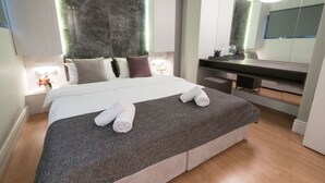 A modern hotel room with a large bed, a built-in desk, a mirror, and a vanity with a sink. - 47 Luxury Suites (Athens)