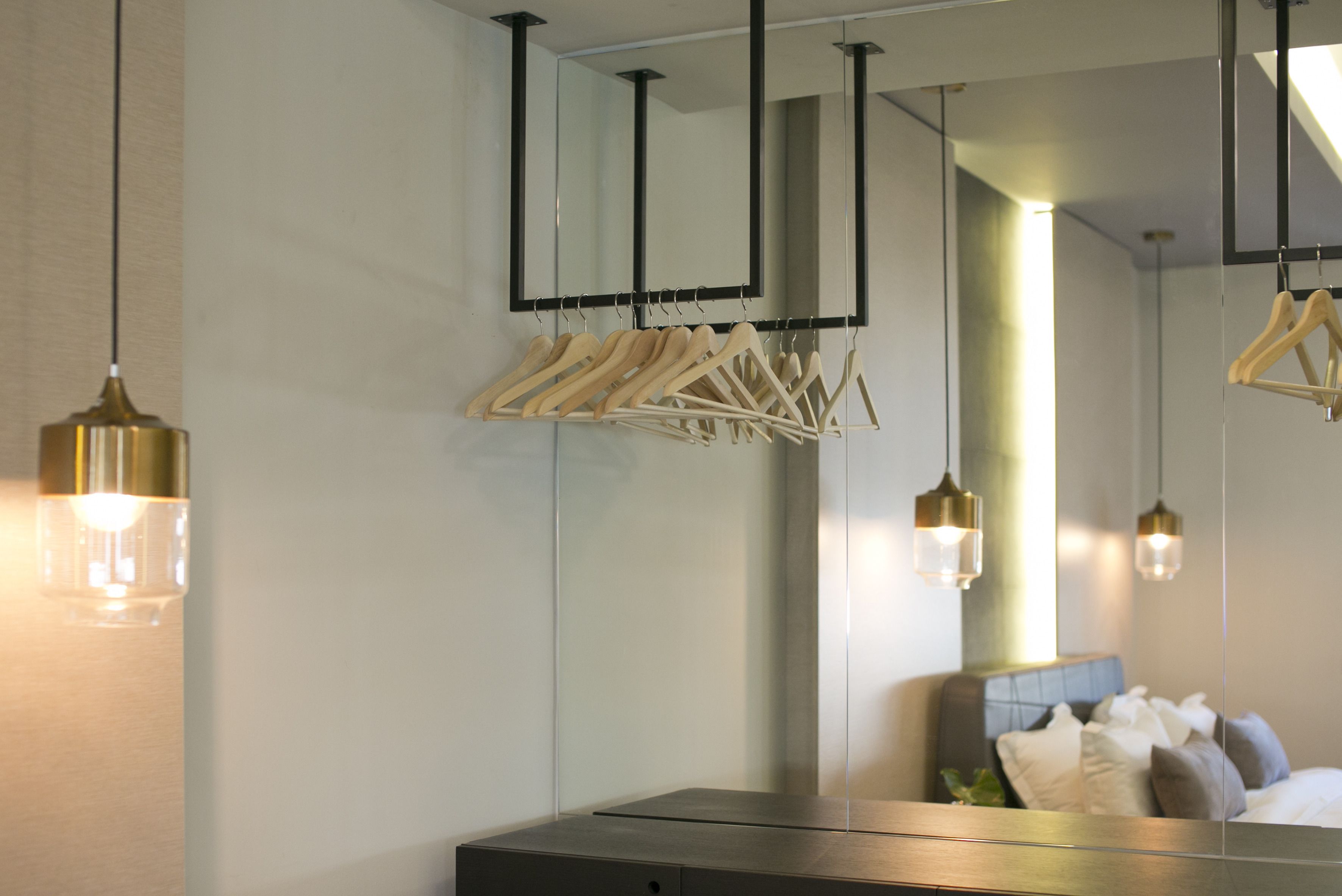 A modern bathroom with a large mirror, wooden hangers, and pendant lights.