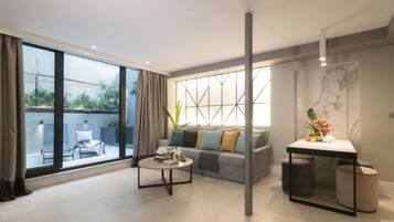 Uma sala de estar moderna com um sofá, mesa de centro e uma pequena mesa com um vaso.