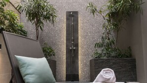 A modern bathroom with a large shower, a towel, and a green pillow on a chair. - 47 Luxury Suites (Athens)