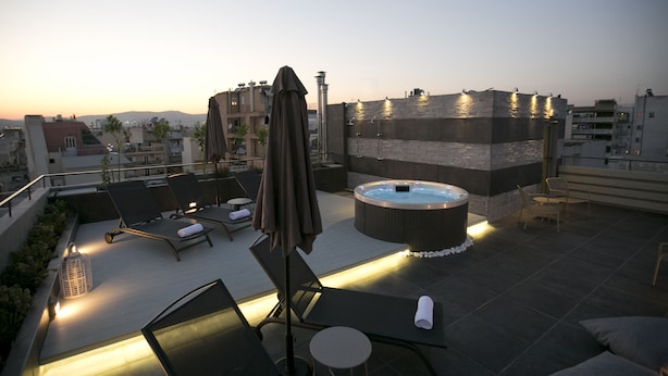A rooftop terrace with lounge chairs, a hot tub, and an umbrella. - 47 Luxury Suites (Athens)