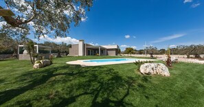 Une maison moderne dotée d’une piscine, entourée d’une pelouse bien entretenue et de rochers.