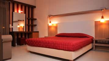 A bedroom with a large bed, a wooden headboard, a bedside table, a mirror, and a small stool.