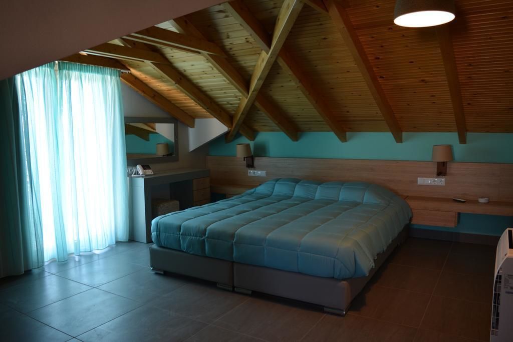 A bedroom with a large bed, wooden ceiling beams, a window with curtains, and a bedside table with a lamp.