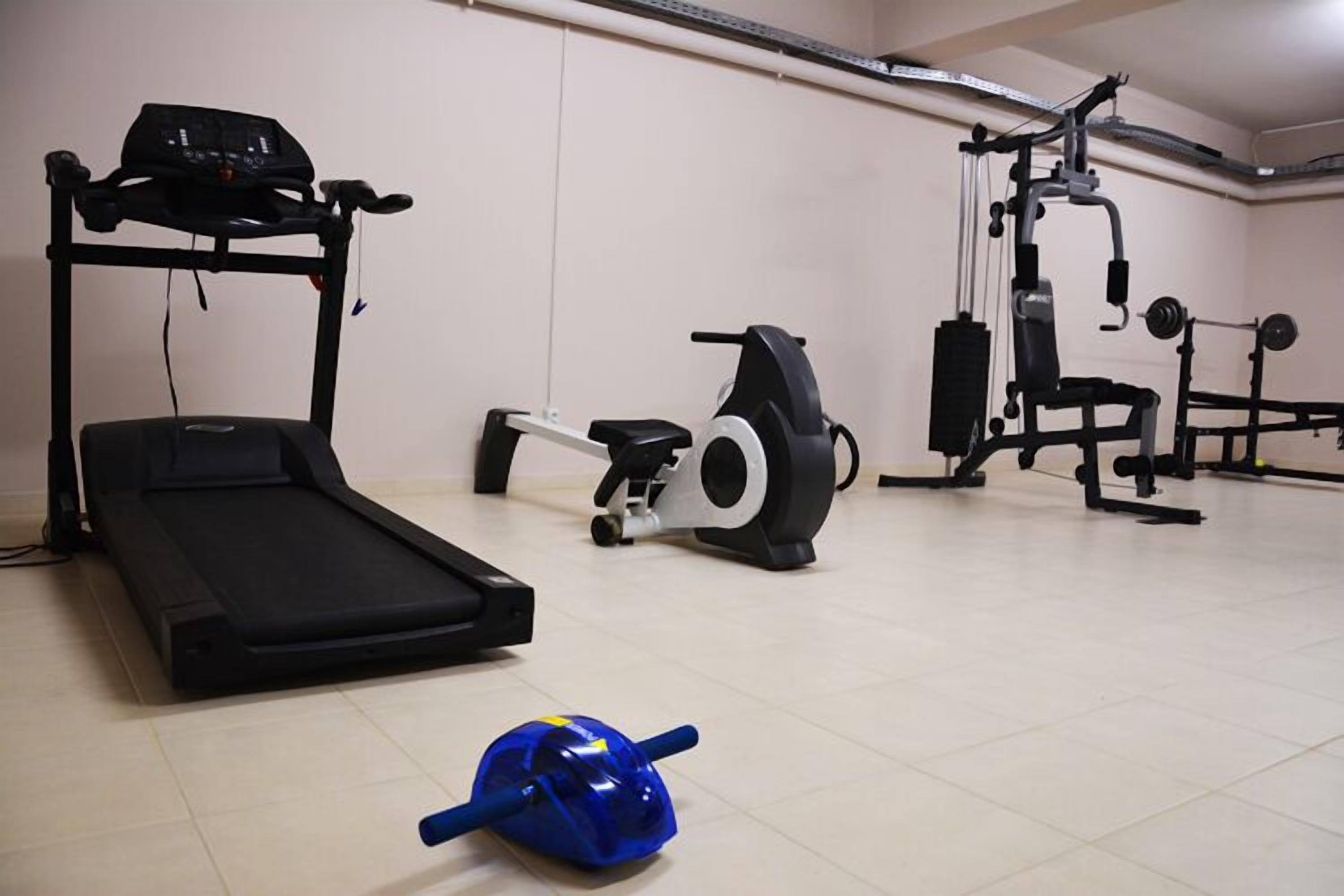 Un gimnasio con cinta de correr, bicicleta estática y máquinas de pesas.