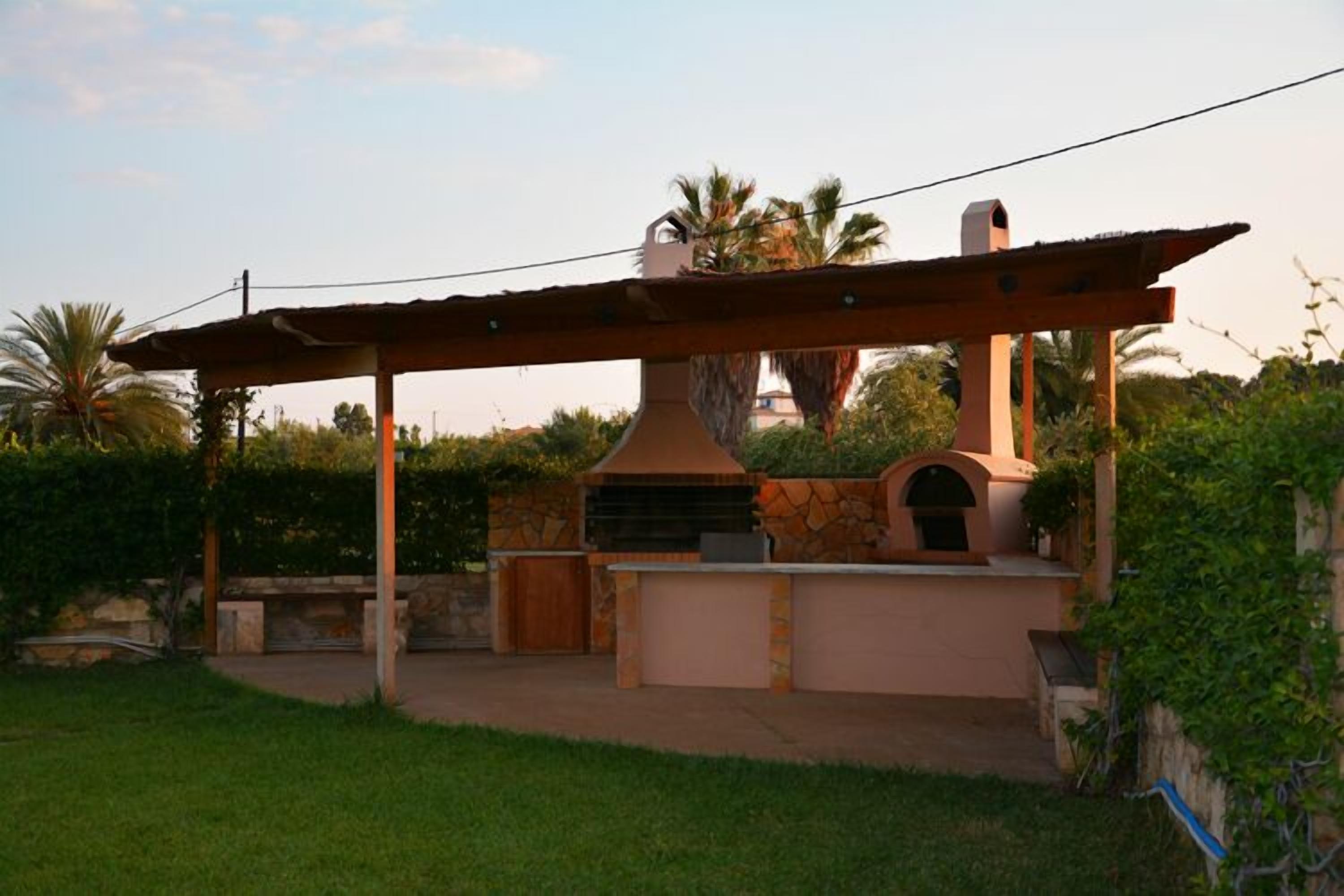 An outdoor kitchen area with a stone structure, a pergola, and a stone wall.