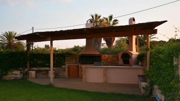 An outdoor kitchen area with a stone structure, a pergola, and a stone wall.