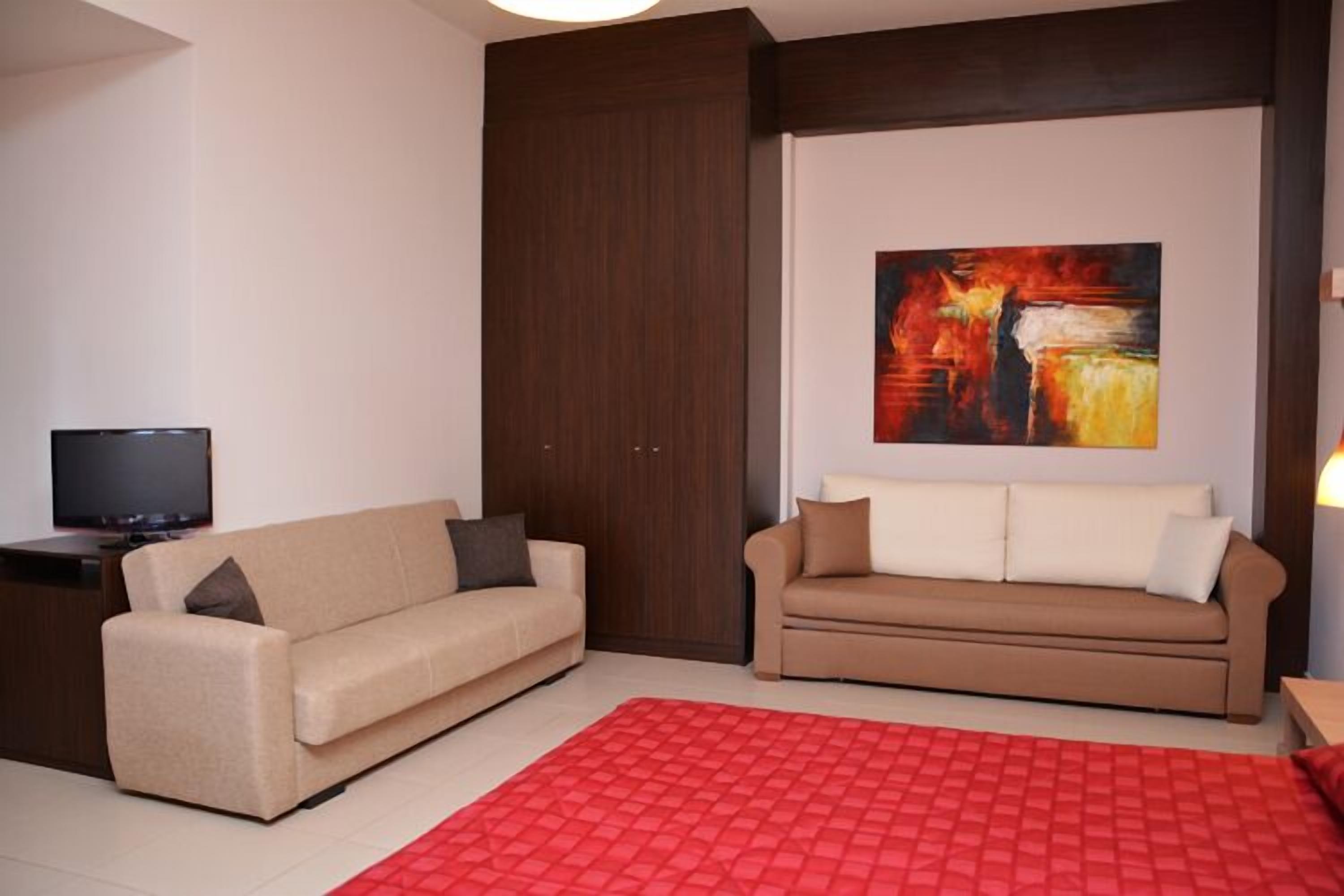 A modern living room with two sofas, a red rug, and a painting on the wall.