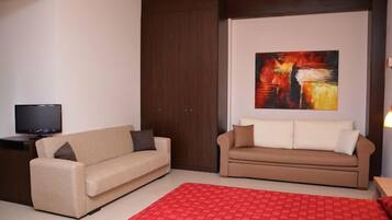 A modern living room with two sofas, a red rug, and a painting on the wall.