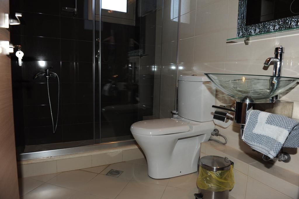 Een moderne badkamer met een douchecabine van glas, een wit toilet en een glazen wastafel.