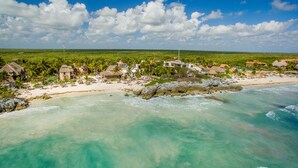 A beach resort with thatched-roof buildings, a sandy beach, and clear turquoise waters. - Maria Del Mar Tulum (Tulum)