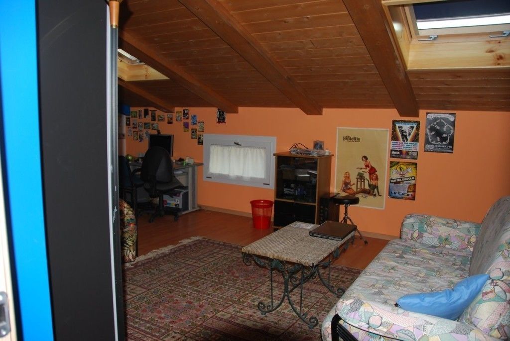 Ein gemütliches Wohnzimmer mit einem gemusterten Teppich, einer Couch, einem kleinen Tisch und einem Fernseher.