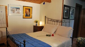 Un dormitorio con cama, mesita de noche, lámpara y cuadros en la pared.