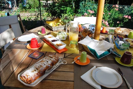 A wooden table set with a variety of food items, including a loaf of bread, a pitcher of juice, and several cups and plates.