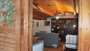 Un interior rústico de madera con comedor, sofá estampado y cama con estructura metálica.