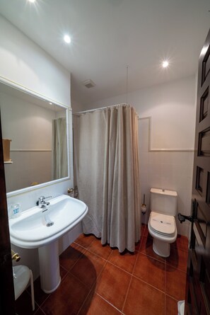 Un baño con lavamanos, inodoro y cortina de ducha.