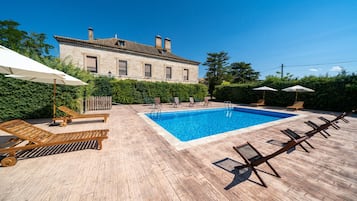 Una piscina al aire libre, sillones reclinables de piscina